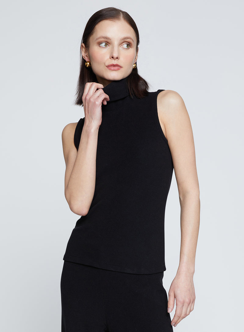 Honeyluxe Flat Back Rib Sleeveless Turtleneck in Black-model is holding her turtle neck and looking away 