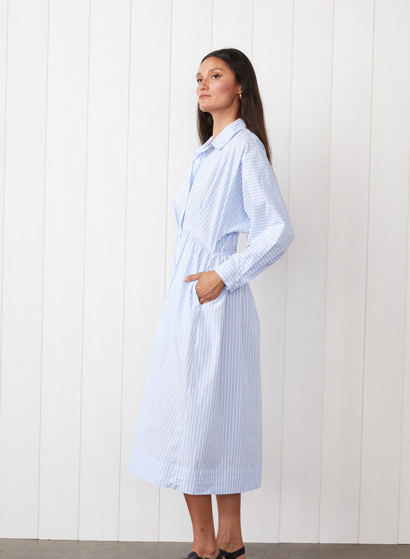 Iberus Stripe Poplin Shirt Dress in Clear Sky Stripe - side view with model having her hands to her side pocket