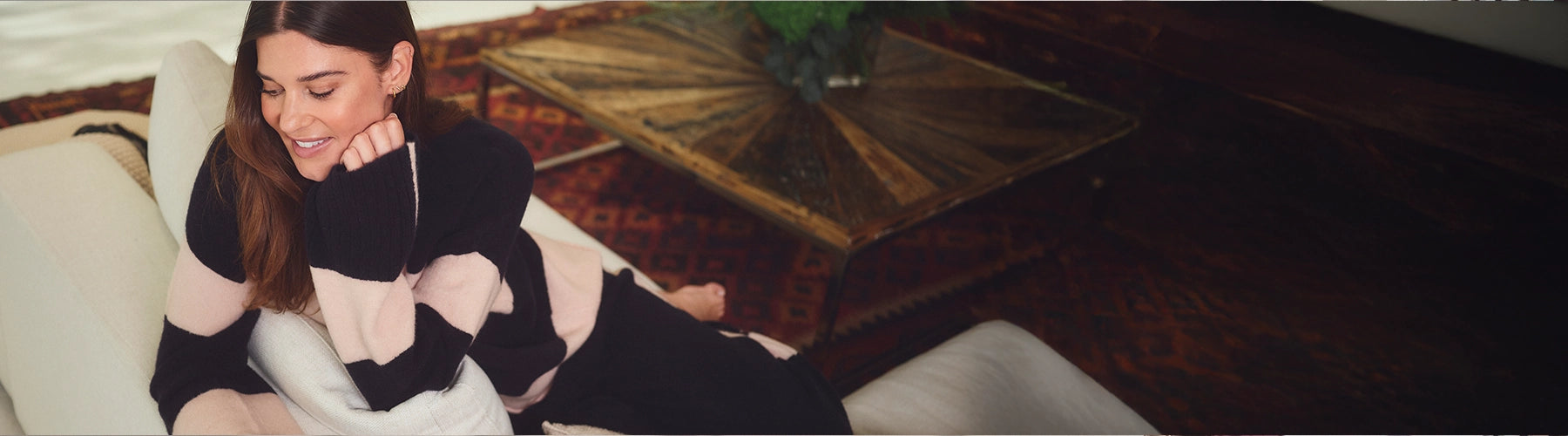 Woman sitting on a couch in a dimly lit room with a painting in the background